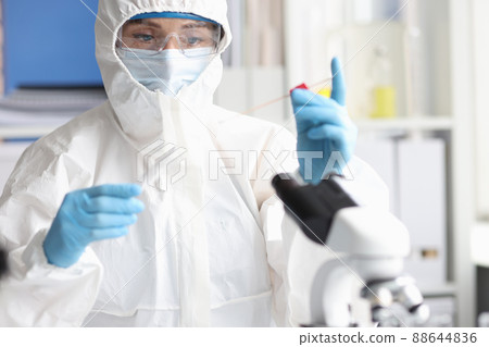 Scientist in protective suit and goggles conducts research in laboratory Scientist in protective suit and goggles conducts research in laboratory 88644836
