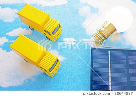 Blue sky, solar panels, light bulbs and two yellow trucks 88644857