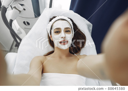 Cosmetology theme. Girl in a white bandage. Woman with mask on face. Cosmetology theme. Girl in a white bandage. Woman with mask on face. 88645380