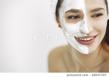 Cosmetology theme. Girl in a white bandage. Woman with mask on face. 88645397