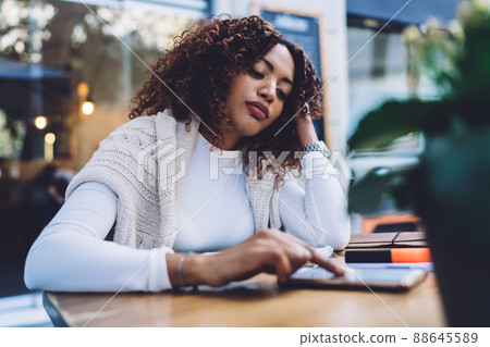 Serious ethnic woman checking smartphone in cafe Serious ethnic woman checking smartphone in cafe 88645589
