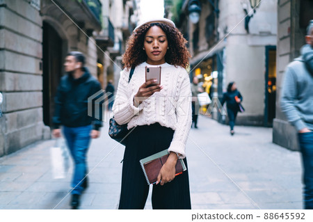Beautiful 20s african american female checking notification on mobile phone of banking app Beautiful 20s african american female checking notification on mobile phone of banking app 88645592