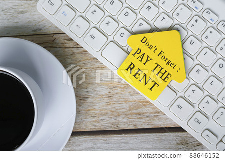 Don't forget, pay the rent text on yellow stick house shape on white keyboard. 88646152
