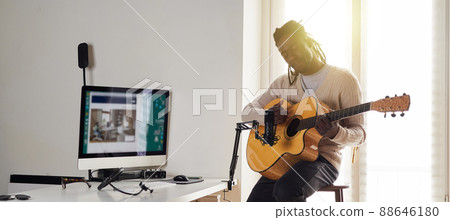 Young man is singing and playing guitar while making an audio recording at home Young man is singing and playing guitar while making an audio recording at home 88646180