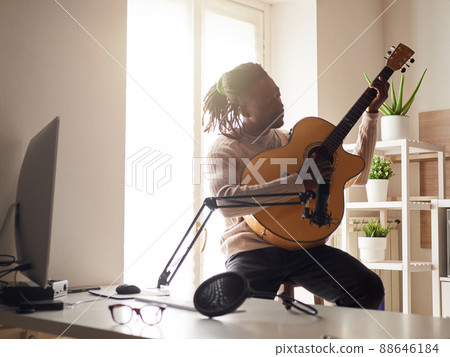 Young man is singing and playing guitar while making an audio recording at home Young man is singing and playing guitar while making an audio recording at home 88646184