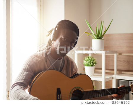 Young man is singing and playing guitar while making an audio recording at home Young man is singing and playing guitar while making an audio recording at home 88646192