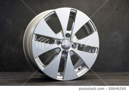 new grey alloy wheels on a dark textured black background. a wheel for a car 88646268
