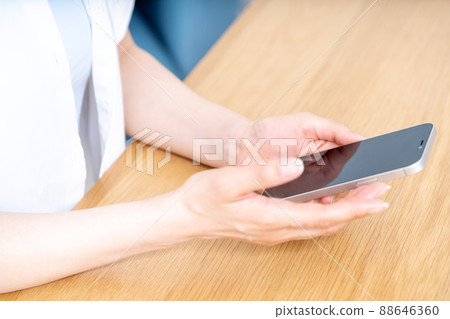 Hands of women who use smartphones at the table [Parts cut] 88646360