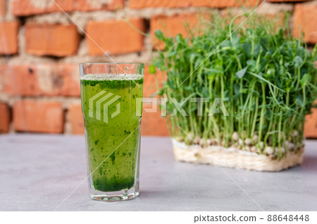 Wheatgrass juice was made from fresh wheat and poured into a glass. 88648448