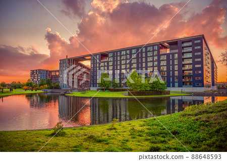 Modern residential building on Tom Kristensens street in orestad city area with lake and green grass at sunset. Copenhagen, Denmark 88648593