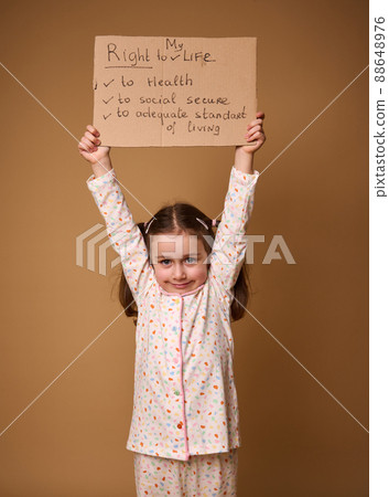 Adorable Caucasian preschool girl holding cardboard poster promoting children's rights to an adequate standard of living, social secure and health care, isolated on a beige background with copy space Adorable Caucasian preschool girl holding cardboard poster promoting children's rights to an adequate standard of living, social secure and health care, isolated on a beige background with copy space 88648976