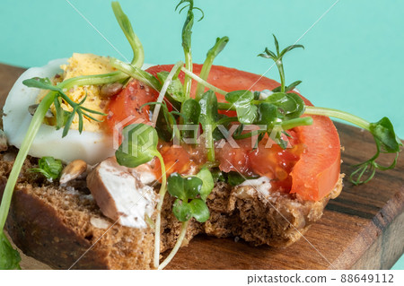 bitten Toast with egg, champignons, tomato and microgreens on a blue 88649112