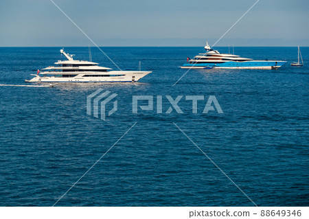 The two huge mega yachts are moored in sea at sunny day, the chrome plated handrail, sun reflection on glossy board of the motor boat The two huge mega yachts are moored in sea at sunny day, the chrome plated handrail, sun reflection on glossy board of the motor boat 88649346
