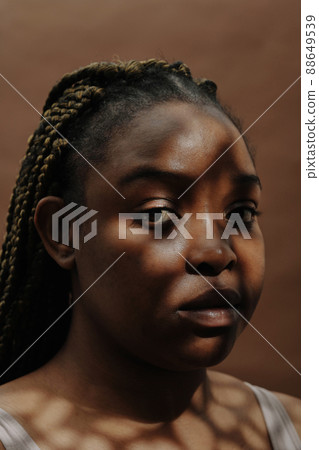 Close-up of African girl with natural beauty looking at camera against the brown background 88649539