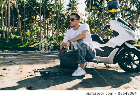 Calm man with scooter and drone on tropical beach Calm man with scooter and drone on tropical beach 88649864