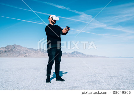Focused man with controller and in VR glasses on lake Focused man with controller and in VR glasses on lake 88649866