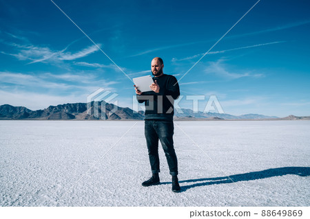 Male explorer browsing tablet in salt pan of Utah state in USA 88649869