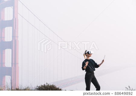 Concentrated woman with tablet in VR headset Concentrated woman with tablet in VR headset 88649892