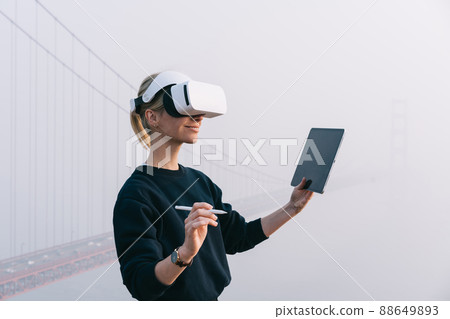 Smiling woman surfing tablet on street Smiling woman surfing tablet on street 88649893