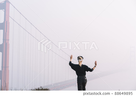 Unrecognizable female using VR goggles in fog Unrecognizable female using VR goggles in fog 88649895