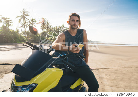 Bearded man sitting on scooter and using phone Bearded man sitting on scooter and using phone 88649949
