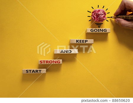 Start strong and keep going symbol. Concept words 'Start strong and keep going' on wooden blocks on a beautiful yellow background. Businessman hand. Business, motivational and start strong concept. 88650620