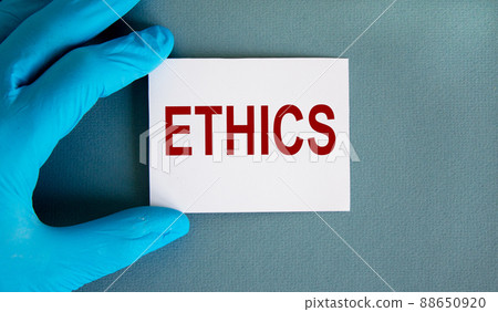 Hand in blue glove with white card. Concept word ethics. Beautiful blue background. 88650920