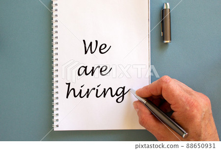 Hand writing 'we are hiring' on white note, isolated on blue background. Hand writing 'we are hiring' on white note, isolated on blue background. 88650931
