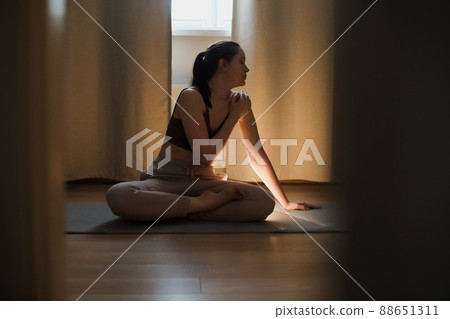 young woman doing yoga and practising meditation on mat at home. mental health concept. fitness yoga training workout. young woman doing yoga and practising meditation on mat at home. mental health concept. fitness yoga training workout. 88651311