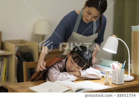 一位母親給在辦公桌前睡著的女兒蓋上毯子 88651754