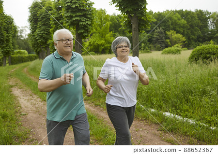 Happy elderly couple retired running in the park in the fresh air. Happy elderly couple retired running in the park in the fresh air. 88652367