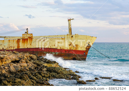 a large rusty shipwreck on a rocky coast against a blue sky background a large rusty shipwreck on a rocky coast against a blue sky background 88652524