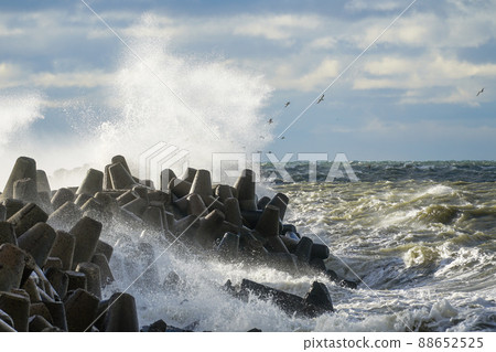 Waves crash on a breakwater during winter storms 88652525