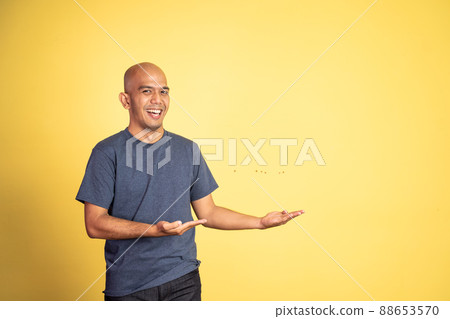 bald man smiling with both hands presenting something bald man smiling with both hands presenting something 88653570