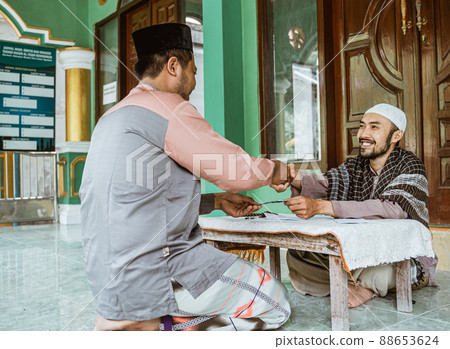 Muslim man shake hand after giving donation and zakat at the mosque Muslim man shake hand after giving donation and zakat at the mosque 88653624