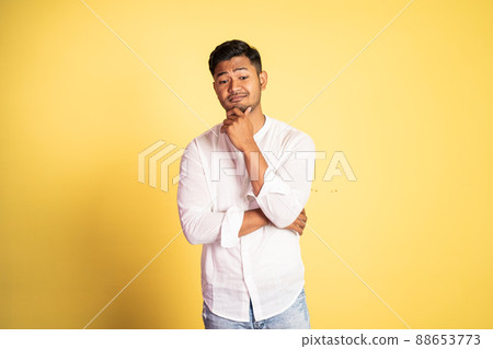 asian young man with sarcastic expression with hand holding chin 88653773