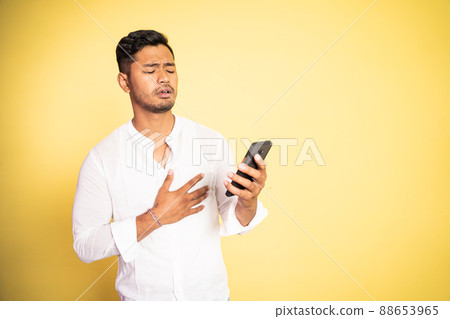 young asian man shocked while watching video using mobile phone young asian man shocked while watching video using mobile phone 88653965