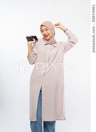 woman using a cell phone and showing excited gesture with arm raised woman using a cell phone and showing excited gesture with arm raised 88654061