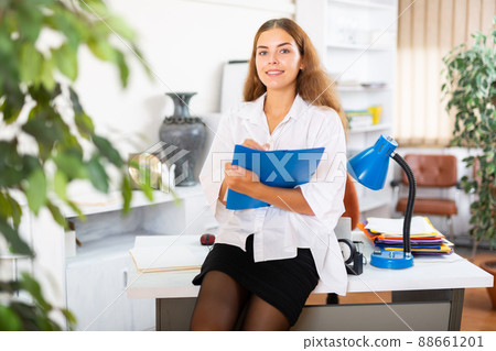 Friendly female administrative secretary writing down tasks in office 88661201