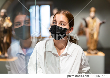 Woman in mask visiting exhibit at sculpture hall in museum 88661552