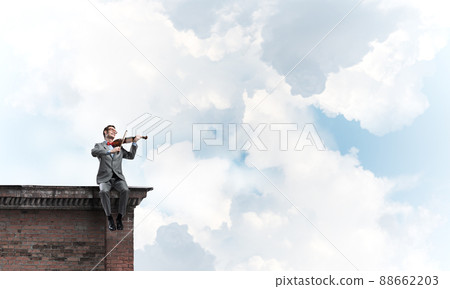 Handsome violinist in glasses on building edge play his melody 88662203