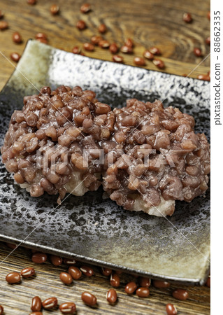 A dark wood-grained back with a black plate full of bean paste and azuki beans scattered randomly (vertical photo) A dark wood-grained back with a black plate full of bean paste and azuki beans scattered randomly (vertical photo) 88662335