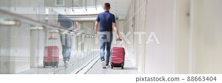 Man with suitcase walking down in hotel corridor back view Man with suitcase walking down in hotel corridor back view 88663404