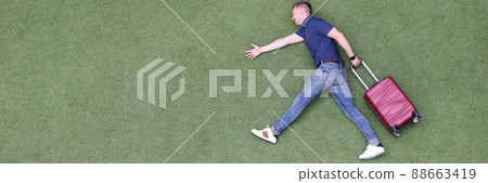 Young man with suitcase walking on green grass top view Young man with suitcase walking on green grass top view 88663419