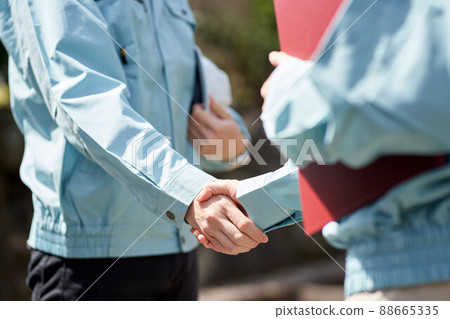 Construction worker shaking hands in front of the building 88665335