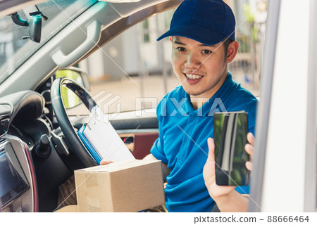 delivery man courier online holding deliveries out boxes inside the car and using mobile smartphone checking location delivery man courier online holding deliveries out boxes inside the car and using mobile smartphone checking location 88666464