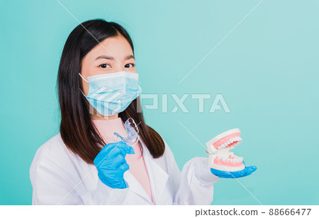 woman dentist holding silicone orthodontic retainers and model teeth denture 88666477