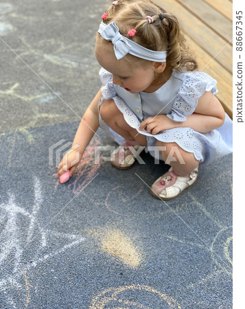 Little girl drawing with colorful chalks on playground 88667345