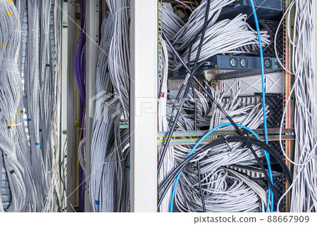 detail of large number of ethernet cables tied together connecting racks inside server room 88667909