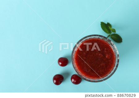 Glass of cherry smoothie and ingredients on blue background Glass of cherry smoothie and ingredients on blue background 88670829